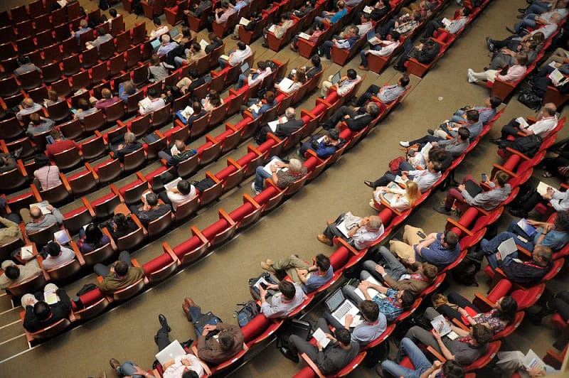 Un public assis dans une large salle qui assiste à une conférence
